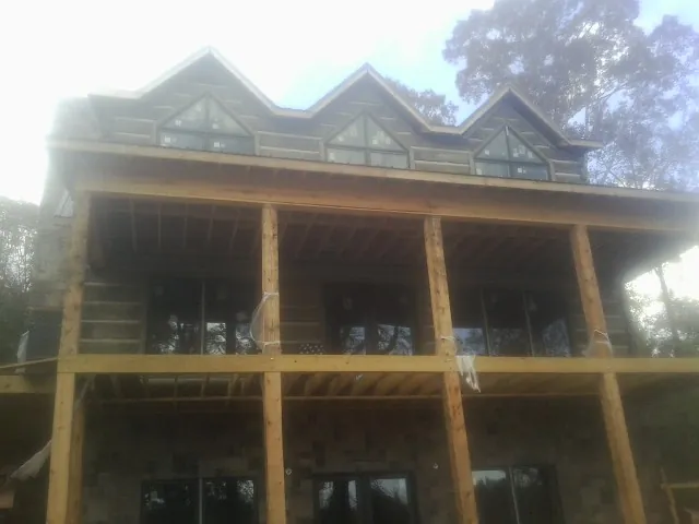 Dormers and porch framing on a large log home under construction — Roof Coating work by our crew in Garden Plain