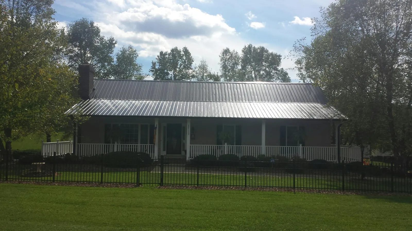 Gray metal roof on a brick ranch with a full width front porch — Gutter Guard Installation work by our crew in Garden Plain