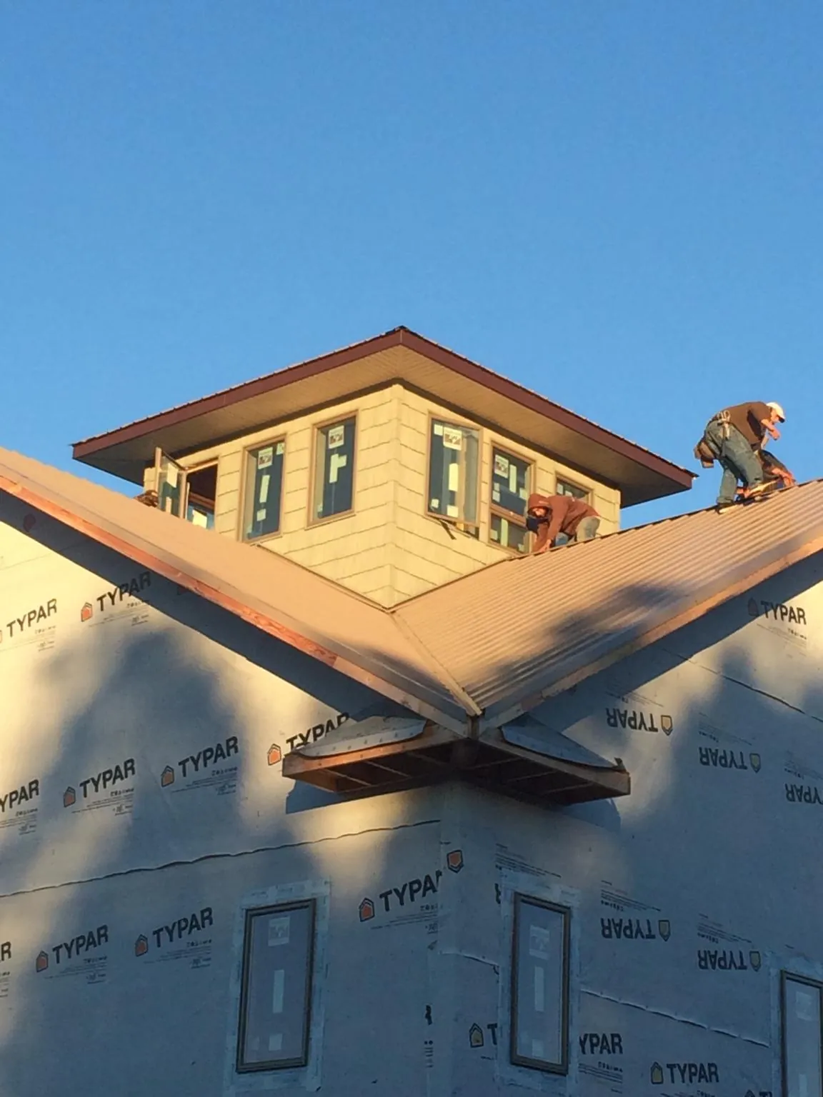Roofers working around a rooftop cupola on a new metal roof at sunset — Roof Waterproofing in Garden Plain by Roofing Brothers